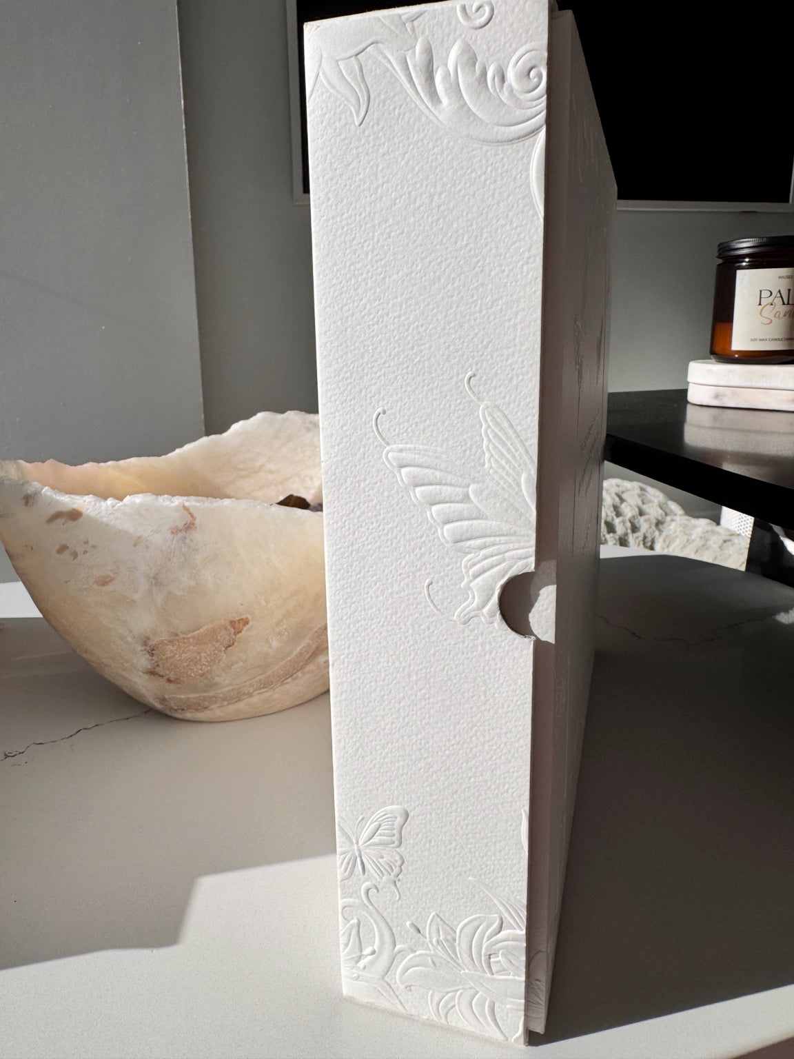 Side profile of the Posoulo premium gift box showing relief-printed butterflies and floral details