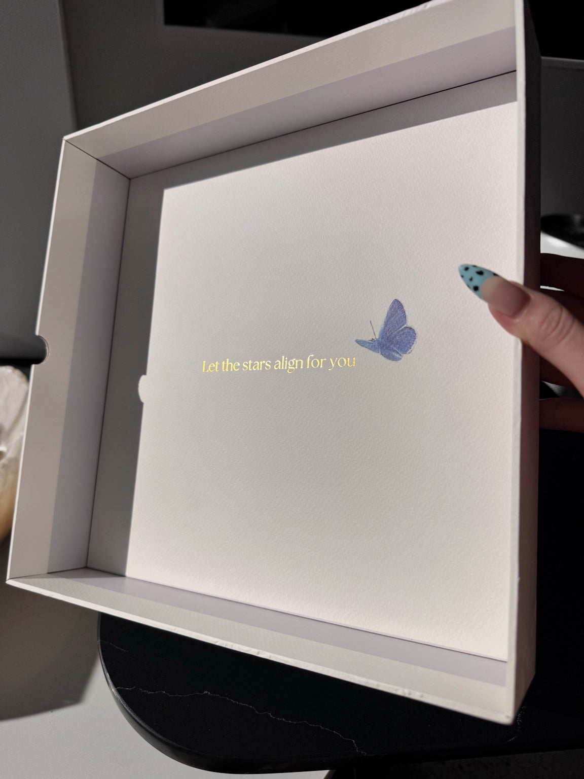 Inside of the Posoulo gift box lid with a blue butterfly and Let the stars align for you message
