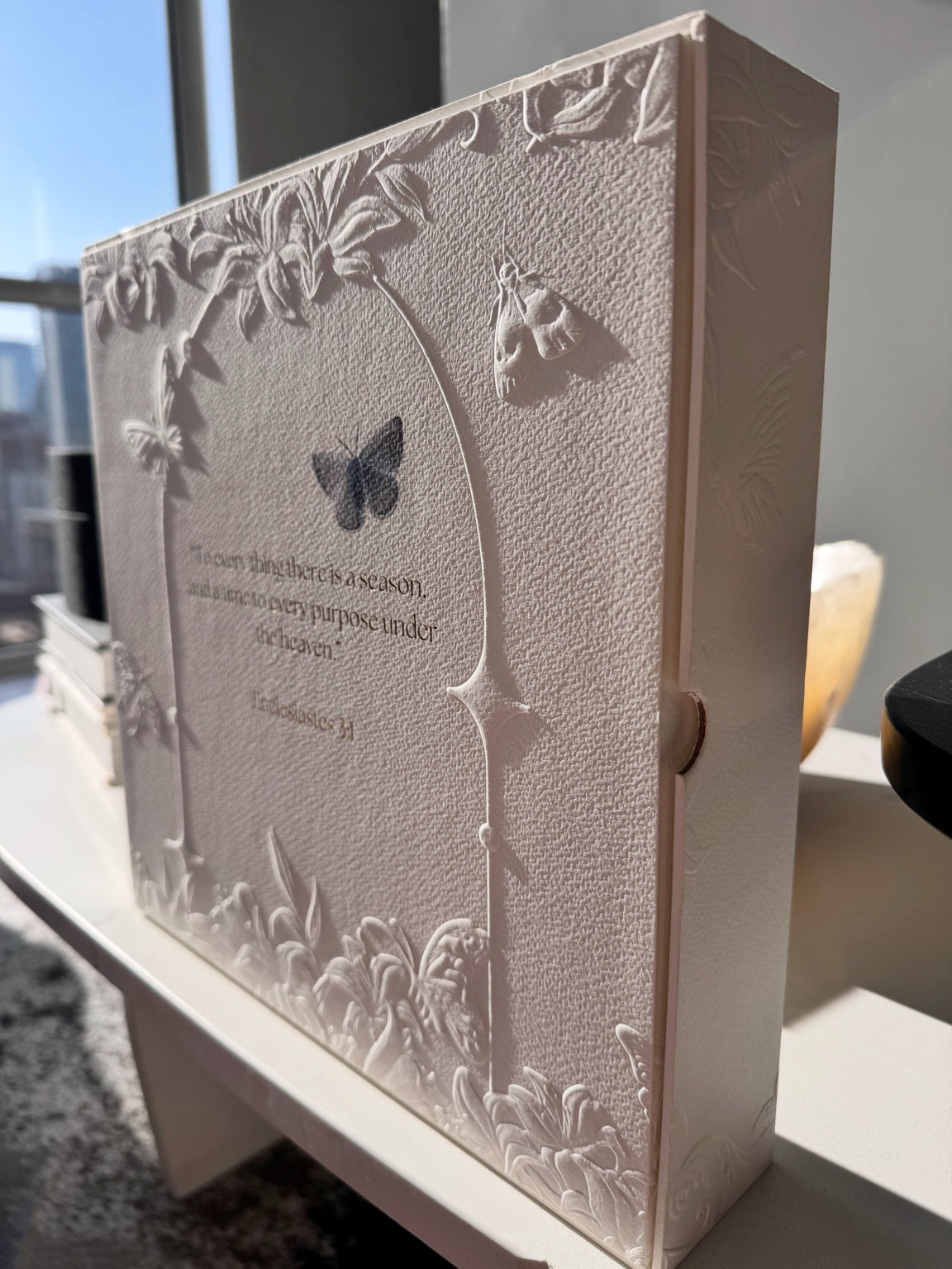 Three-quarter side view of the Posoulo gift box back showing relief printing and Ecclesiastes 3:1
